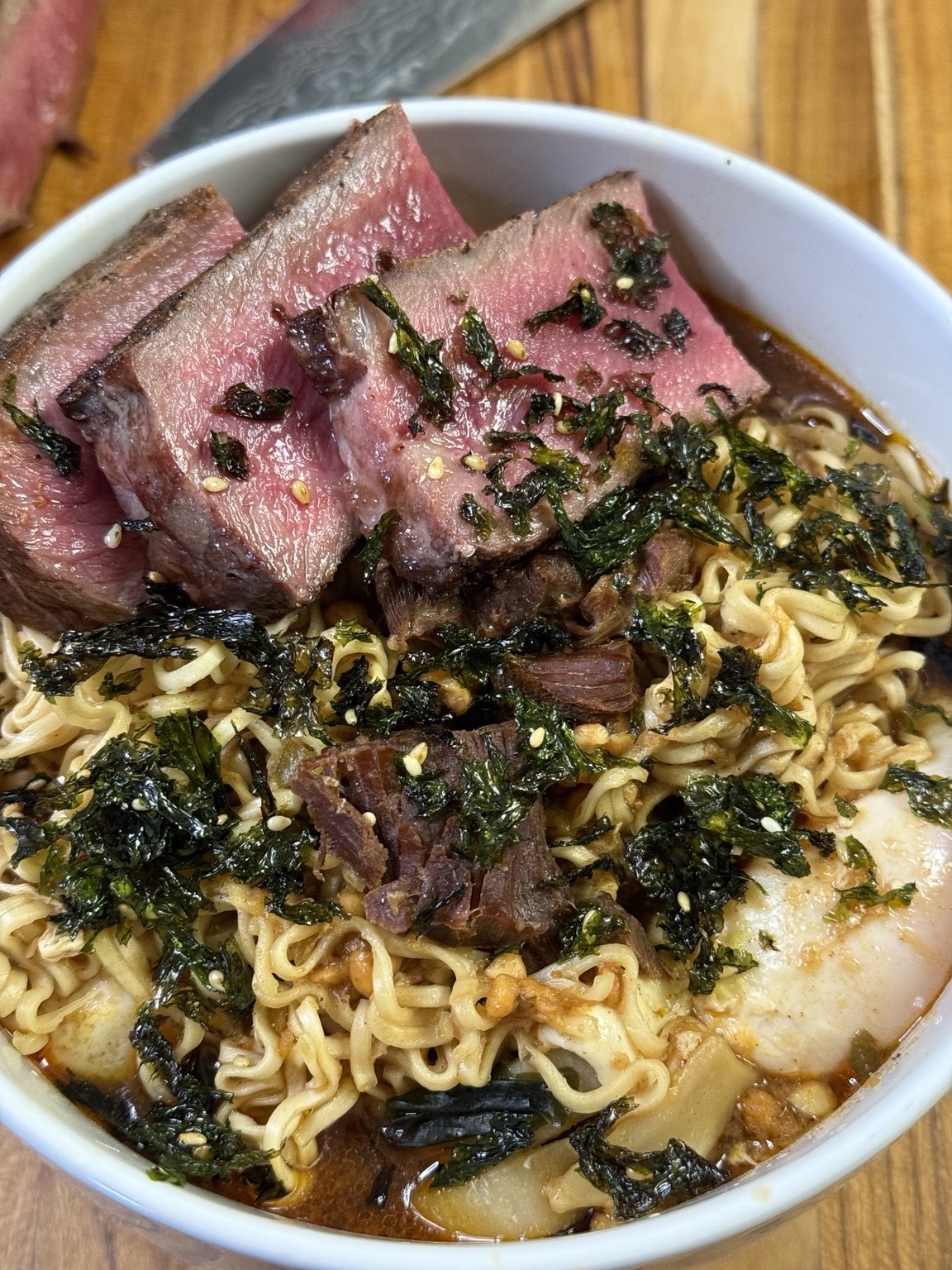 Noodle bowl topped with sliced beef and herbs